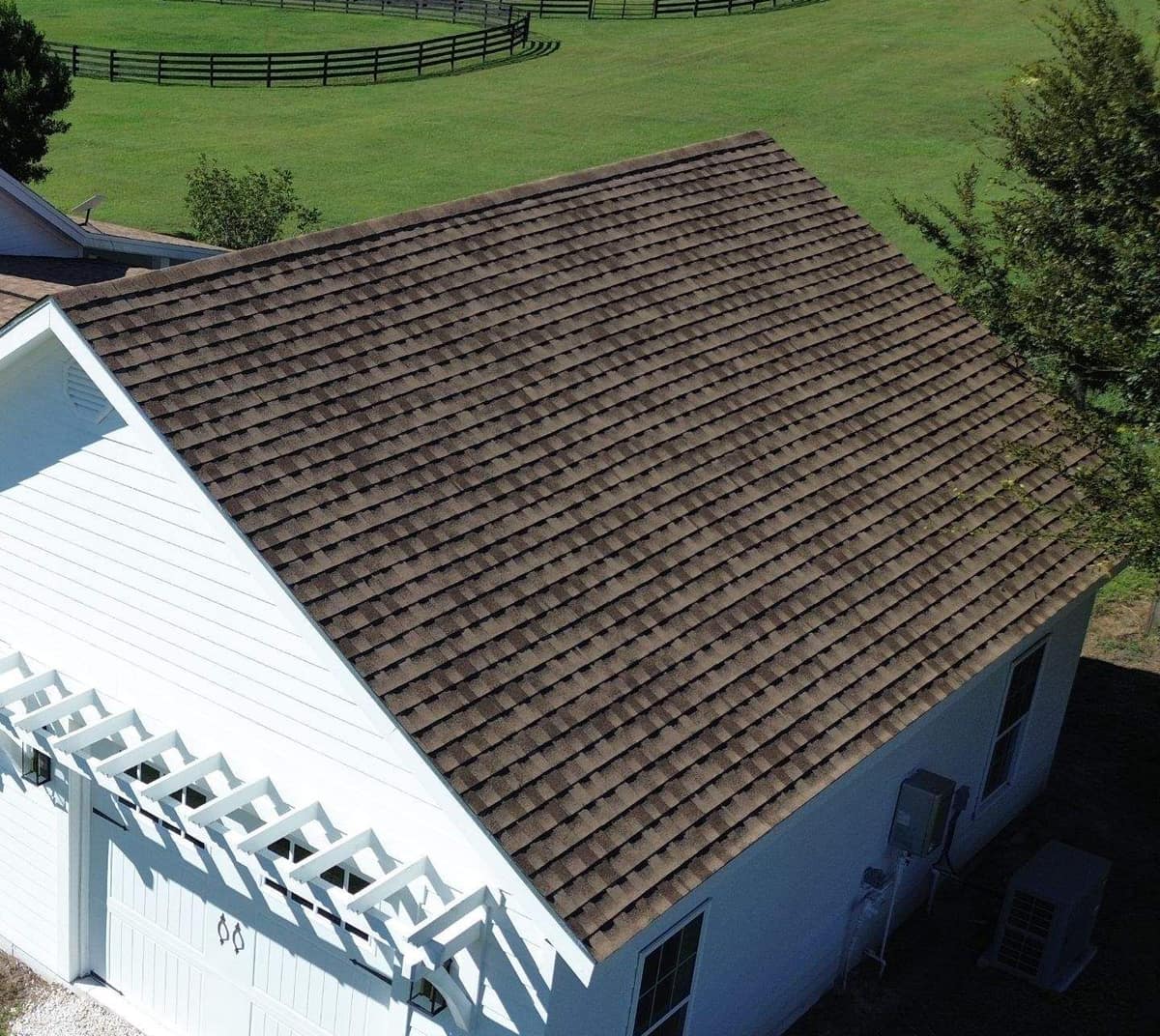 Garage wing of the Ocala home with a white pergola over the door and a new shingle roof