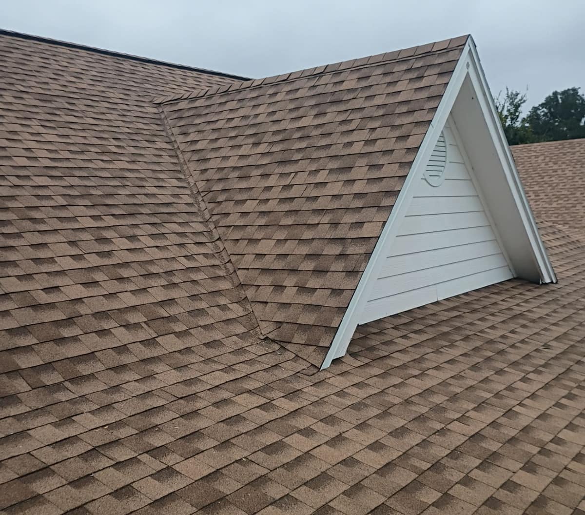 Front dormer with white lap siding meeting the main roof in a shingled valley in Ocala
