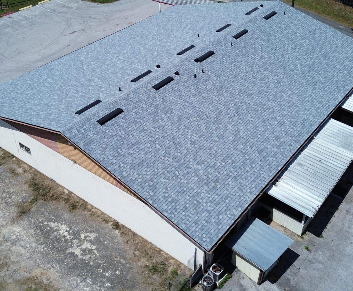 Drone view of a large commercial building in Reddick with a new light blue-gray shingle roof