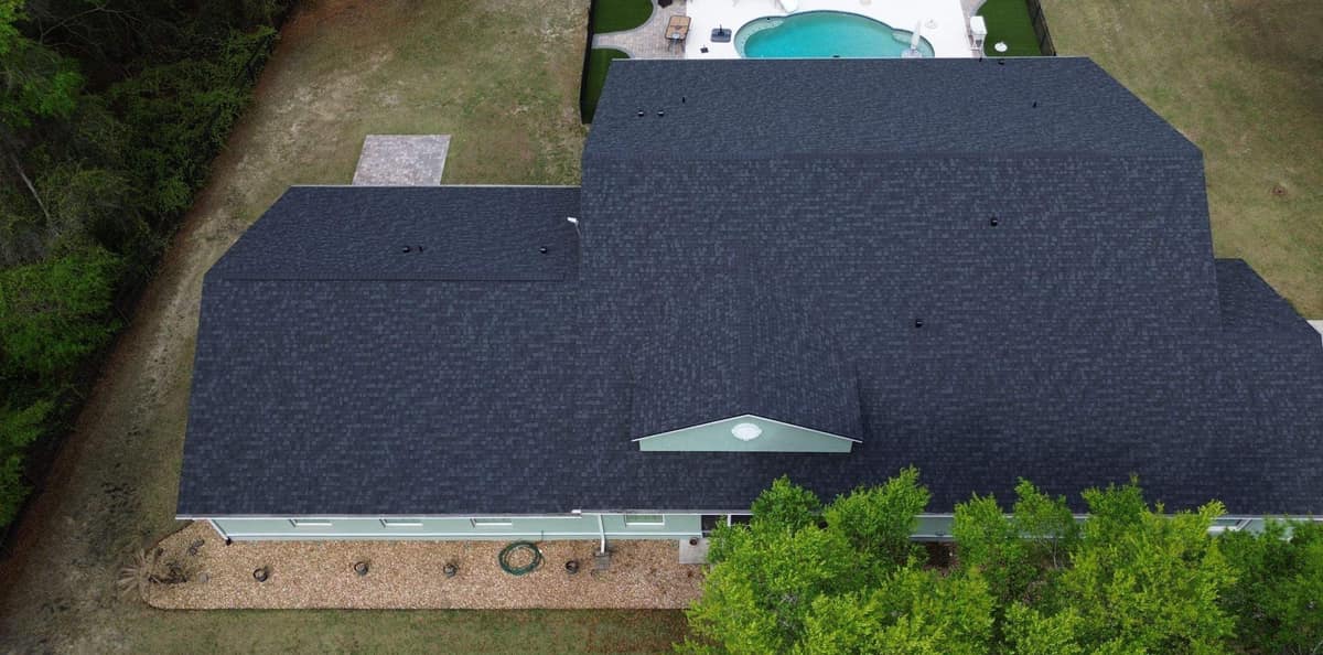 Overhead drone view of the new charcoal gray shingle roof on a Summerfield home with a pool