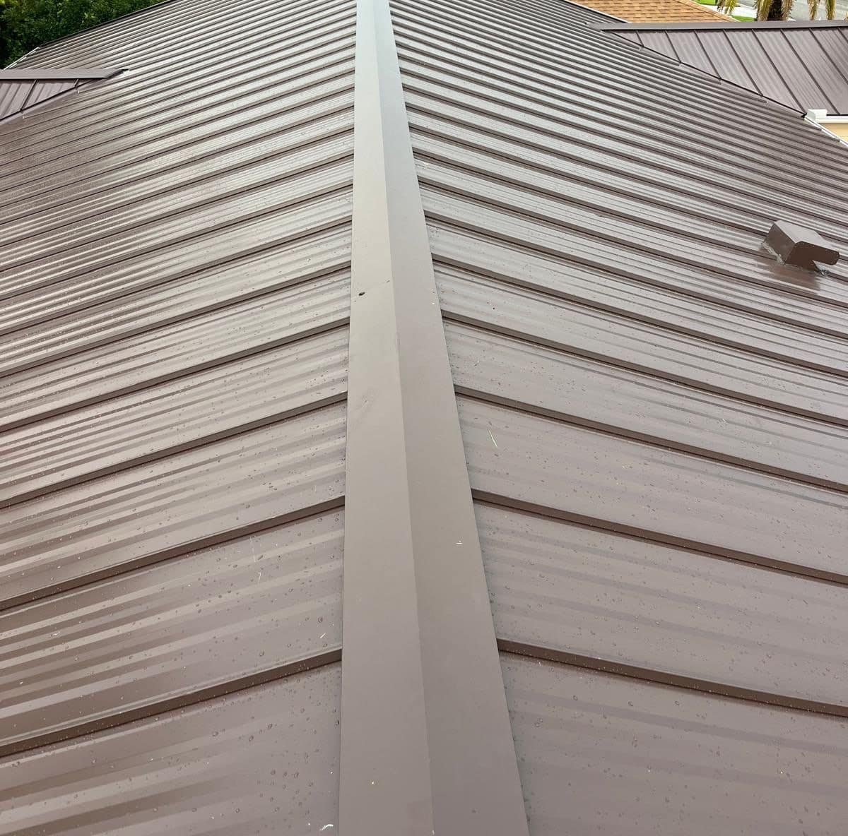 Main ridge of a new brown standing seam metal roof in The Villages, with a box vent