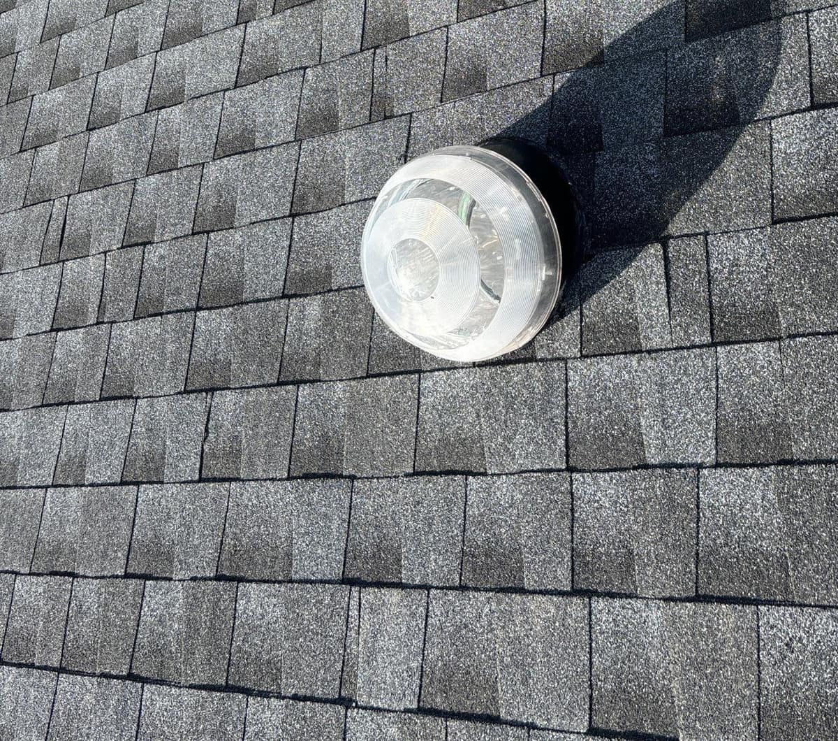 Clear dome of a solar tube skylight set in the new shingles in The Villages