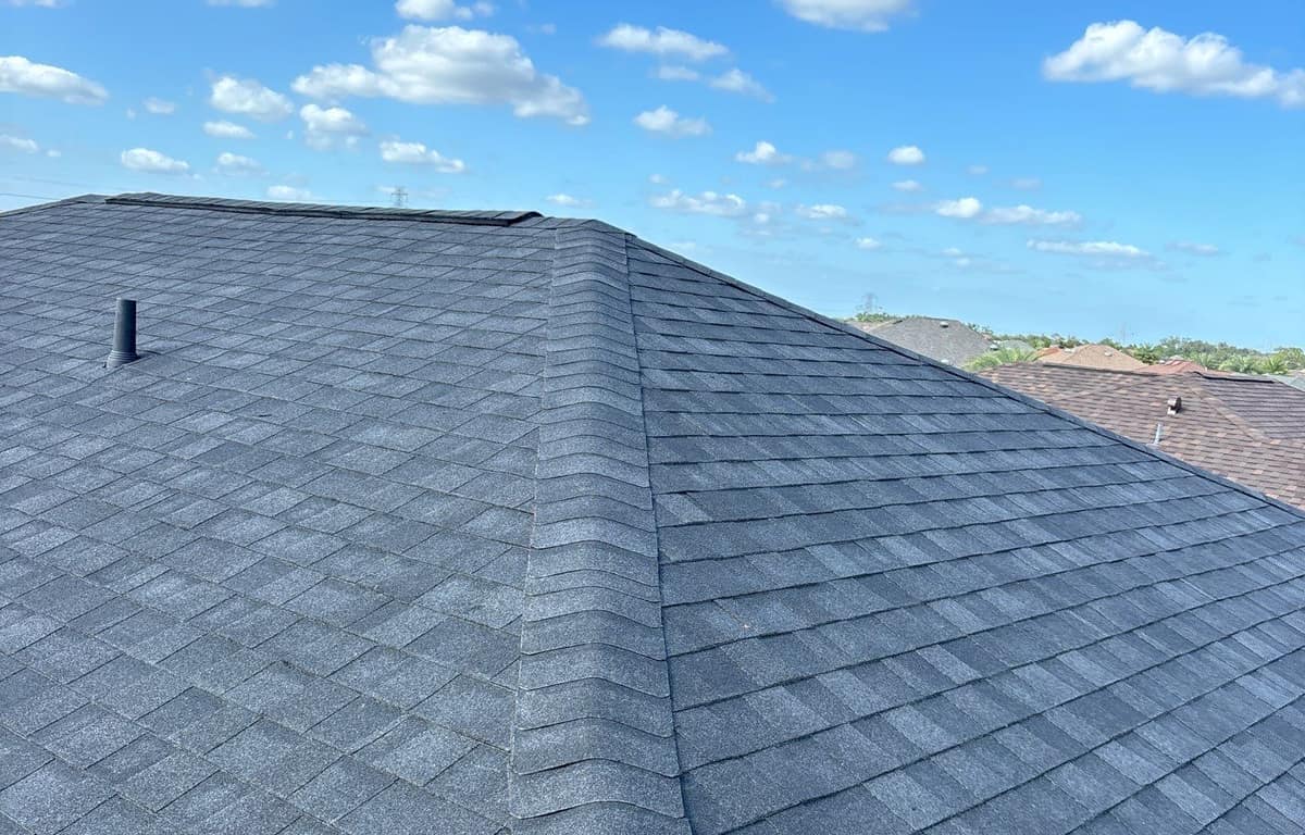 Charcoal gray shingle hip rising to the main ridge under a blue sky in The Villages