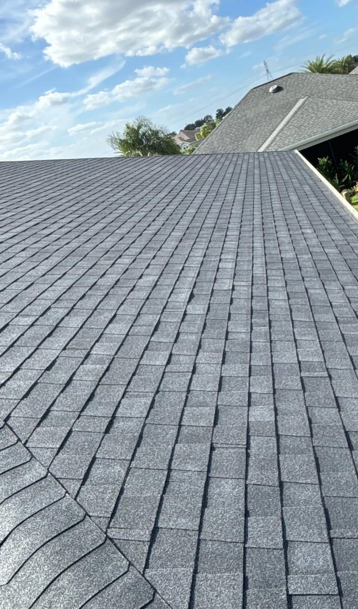 Long slope of new charcoal architectural shingles running down to the white gutter on The Villages home