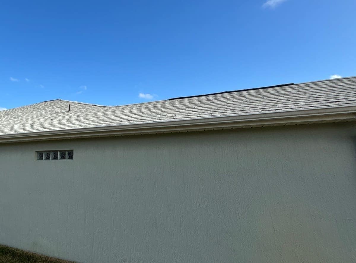 Pale gray stucco wall and a glass block window below the new shingle roofline in The Villages