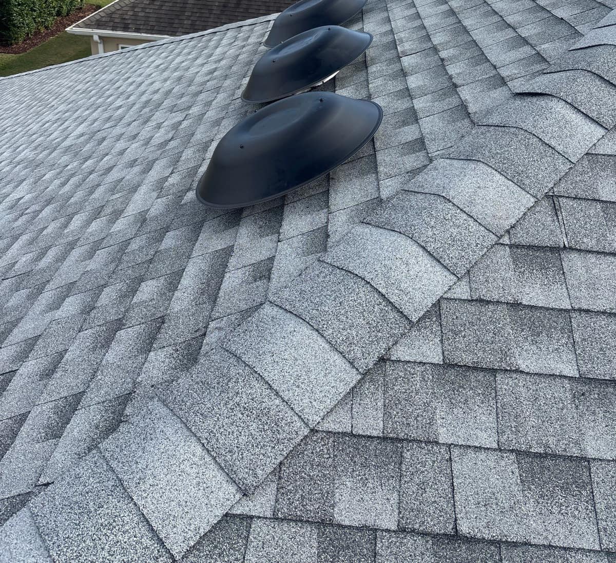 Three dark gray round roof vents in a row beside a hip, The Villages
