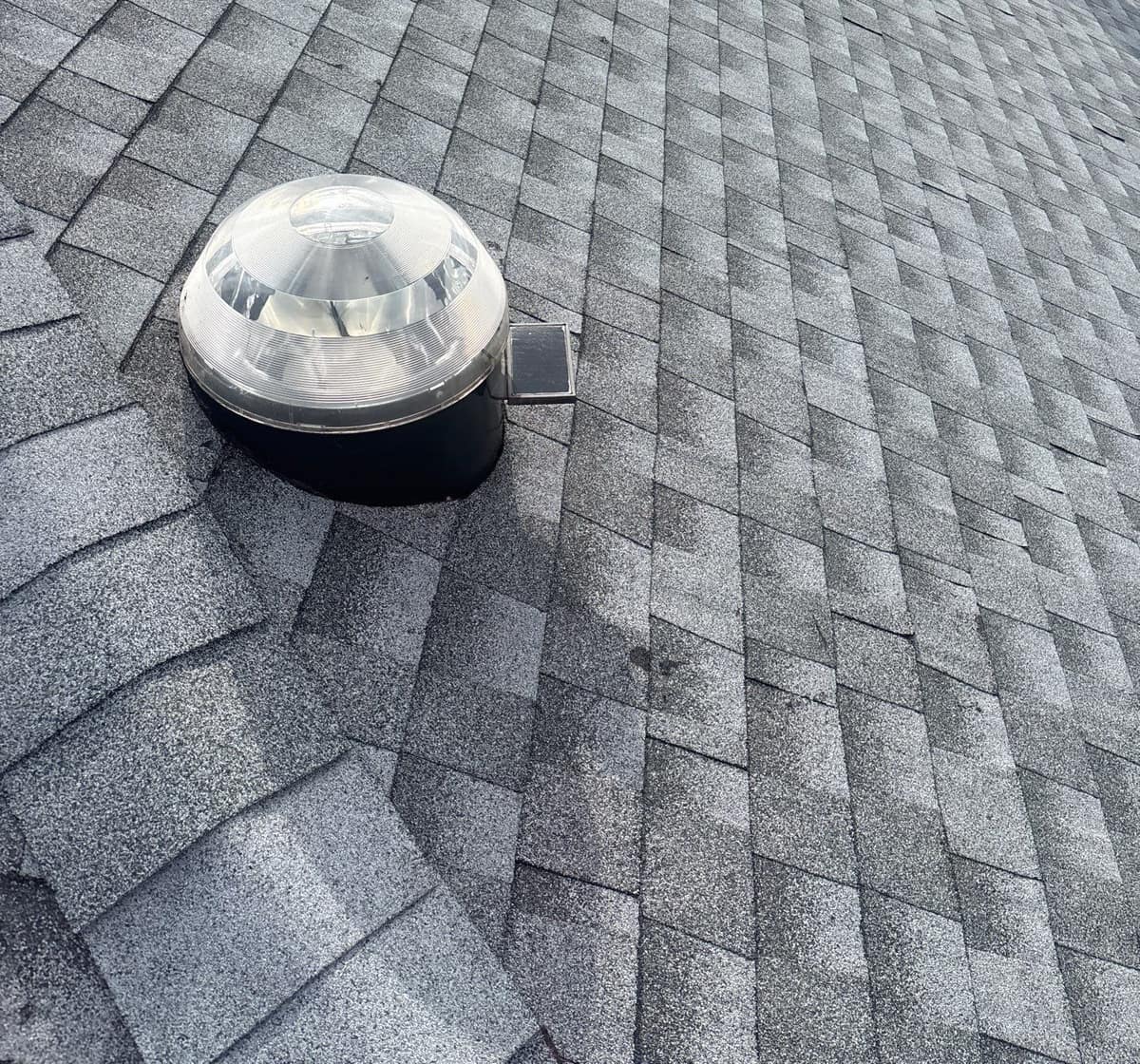 Clear tubular skylight dome with a small solar panel, set into new shingles in The Villages