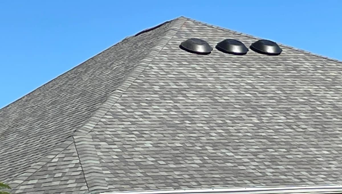 Hip roof in The Villages with new gray blend shingles and three round vents near the peak