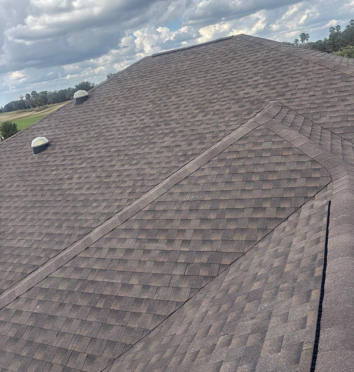 Main slope of the new brown and gray shingle roof in The Villages, with two skylight domes