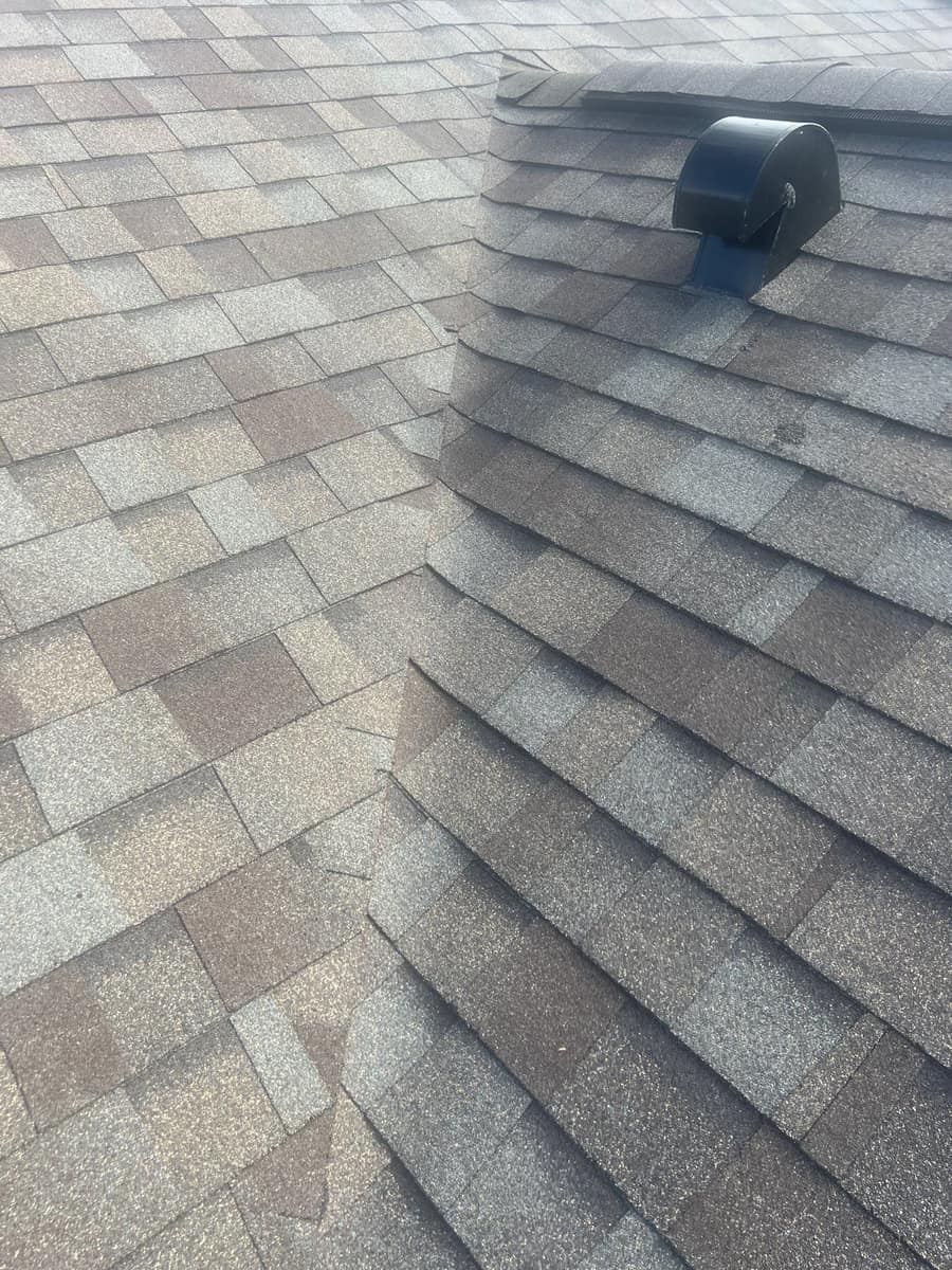 Close view of a shingled valley and a black hooded vent on the roof in The Villages