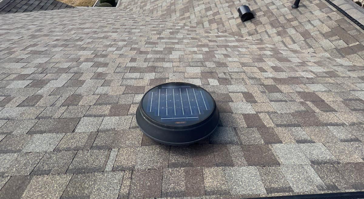 Round solar attic fan set into the new tan and taupe shingles in The Villages