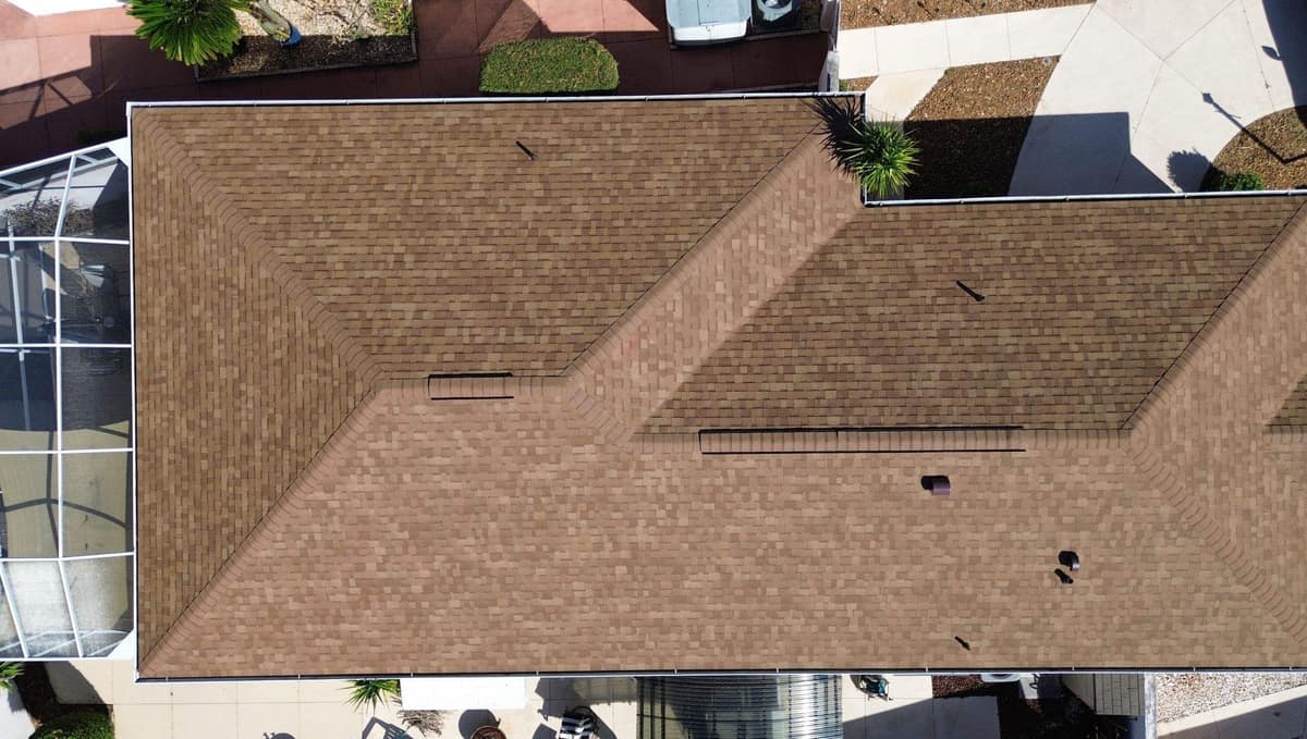 Top-down drone view of a new tan shingle hip roof with two ridge vents in The Villages